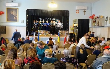 2.	Zdjęcie gości, kt&oacute;rzy wzięli udział w koncercie &bdquo;Razem z Wami&rdquo;- koncert artystek z Ukrainy. Koncert odbył się w Sali Domu Ludowego w B&oacute;brce. Na zdjęciu widoczna r&oacute;wnież scena podczas występu artystek z Ukrainy. .  