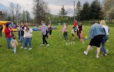 Dzieci bawiące się na murawie Kompleksu Boisk Sportowych w Chork&oacute;wce. W tle widać dmuchana zjeżdżalnię. 