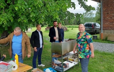 Stoisko kulinarne. Na zdjęciu trzej mężczyźni grillują kiełbasę. 