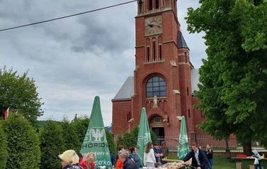 Stoiska kulinarne podczas VI Przeglądu, w tle widać miejscowy kości&oacute;ł wykonany z czerwonej cegły 