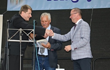 Ksiadz wręcza dyplom w&oacute;jtowi Gminy Chork&oacute;wka. Na zdjęciu r&oacute;wnież sołtys wsi B&oacute;brka. 