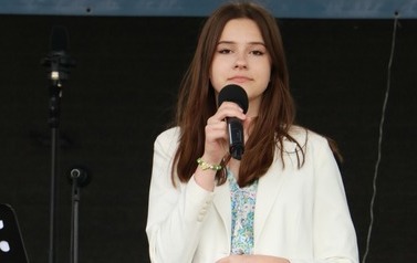 Solistka w niebieskiej sukience oraz białej marynarce. 