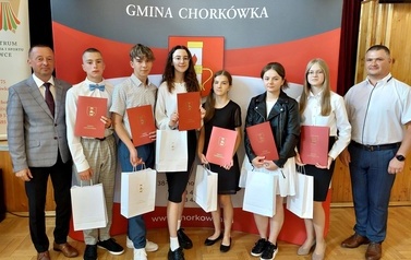 Grupa nagrodzonych uczni&oacute;w w towarzystwie w&oacute;jta oraz dyrektora szkoły. 
