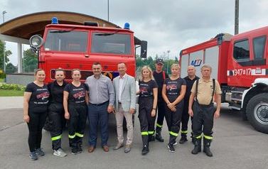 Zdjęcie grupowe strażak&oacute;w na tle przekazywanego samochodu. 