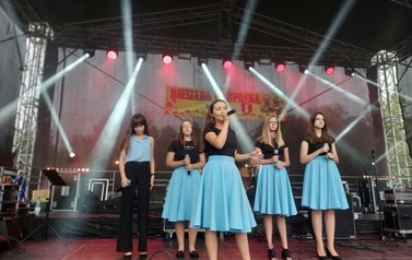 Na fotografii grupa wokalna działająca przy Centrum Kultury. Dziewczyny ubrane w czarne bluzki i niebieskie sp&oacute;dnice. 