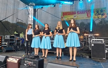 Na fotografii grupa wokalna działająca przy Centrum Kultury. Dziewczyny ubrane w czarne bluzki i niebieskie sp&oacute;dnice. 