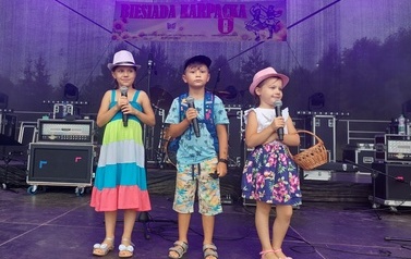 Troje dzieci, dwie dziewczynki i chłopiec w kolorowych letnich stylizacjach.. 