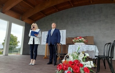 Narodowe czytanie w Gminie Chork&oacute;wka. Stacjonarna scena a na niej szyld Narodowego czytania, na białym tle czarne litery i napis Narodowe czytanie, wplecione elementy czerwone. Na scenie okrągły stolik na nim czerwony bukiet. Przy stoliku krzesła na kt&oacute;ry