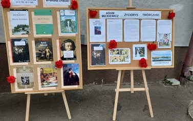 Zdjęcie drewnianych sztalug a na nich okolicznościowa wystawa poświęcona  tw&oacute;rczości Adama Mickiewicza. 