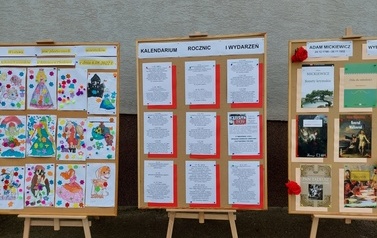 Na zdjęciu drewniane sztalugi z przygotowana prezentacją tw&oacute;rczości Adama Mickiewicza. 