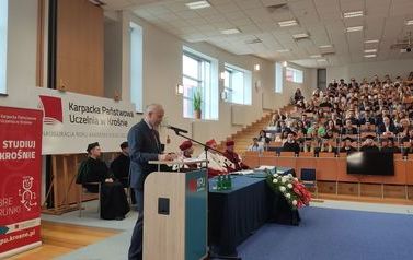 Inauguracja roku akademickiego. Zdjęcie absolwent&oacute;w w auli oraz gości przemawiających.