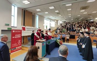 Inauguracja roku akademickiego. Zdjęcie absolwent&oacute;w w auli oraz gości przemawiających.