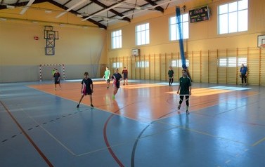 Na parkiecie Hali sportowej w Świerzowej Polskiej odbywają się rozgrywki w halowej piłce nożnej. Zdjęcie przedstawia drużyny w czasie meczu.