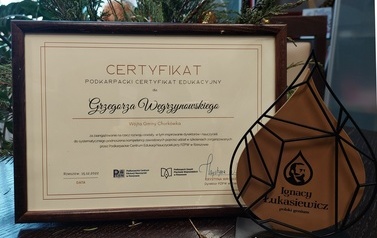 Zdjęcie otrzymanej pzrez w&oacute;jta statuetki w kształcie kropli ropy oraz dyplomu oprawionego w drewnianą ramkę. 