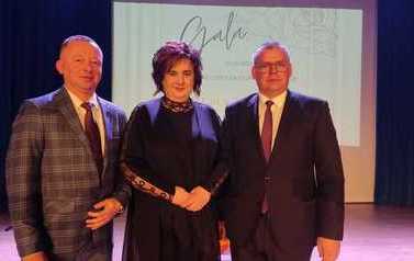 Trzy elegancko ubrane osoby pozują do fotografii. 