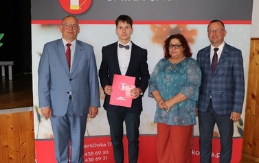 Zdjęcie ucznia z przedstawicielami gminy i dyrektorem. 