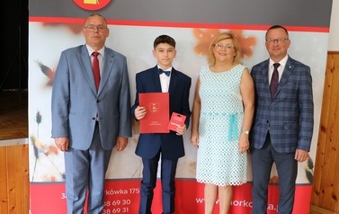 Zdjęcie ucznia z przedstawicielami gminy i dyrektorem. 