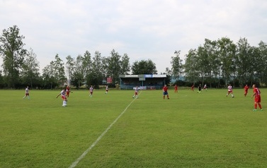 Zdjęcie wykonane podczas meczu. Zawodnicy na boisku sportowym braja w piłkę nożną. 