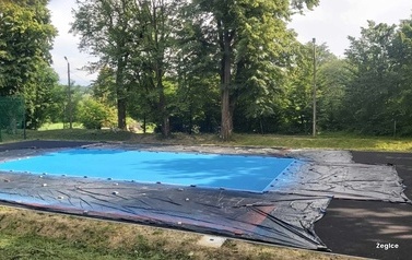 Widoczne w oddali boisko sportowe w kolorze niebieskim.