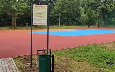 Widoczne w oddali boisko sportowe w kolorze niebiesko-pomarańczowym.