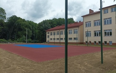 Widoczne w oddali boisko sportowe w kolorze niebiesko-pomarańczowym.