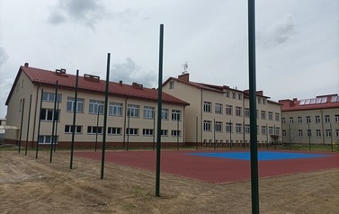 Widoczne w oddali boisko sportowe w kolorze niebiesko-pomarańczowym.