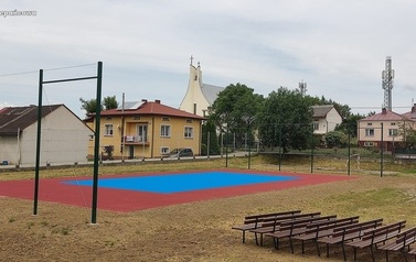 Widoczne w oddali boisko sportowe w kolorze niebiesko-pomarańczowym.