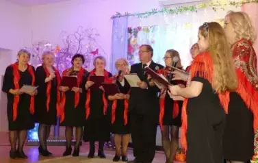 Zesp&oacute;ł Nadzieja. Kobiety i mężczyźni w ciemnych strojach i czerwonych akcentach w postaci chusty. 