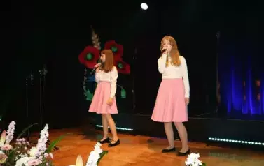 Dwie dziewczynki w białych bluzkach i niebieskiej oraz r&oacute;żowej sp&oacute;dnicy.