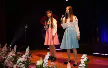 Dwie dziewczynki w białych bluzkach i niebieskiej oraz r&oacute;żowej sp&oacute;dnicy.