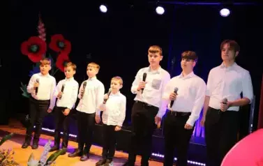 Na scenie sami chłopcy w białych koszulach i ciemnych spodniach. 