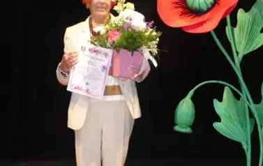 Kobieta w jasnym garniturze z bukietem kwiat&oacute;w. 