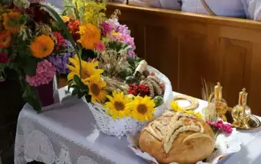 Dary przygotowane na wręczenie księdzu podczas mszy. Chleb, wino, kwiaty 