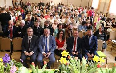 Zdjęcia dokumentują wysoką frekwencję mieszkańc&oacute;w. W pierwszych rzędach zasiadają przedstawiciele samorządu i lokalni liderzy, co podkreśla rangę wydarzenia dla całej gminy. Atmosfera jest uroczysta, a jednocześnie pełna ciepła i sąsiedzkiej życzliwości.
