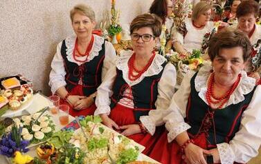 Zdjęcia ukazują bogactwo podkarpackiego folkloru. Członkinie KGW z całej gminy prezentują się w tradycyjnych strojach: białych, haftowanych bluzkach z kryzami oraz charakterystycznych czerwonych koralach. Siedzą przy stołach uginających się od tradycyjnyc