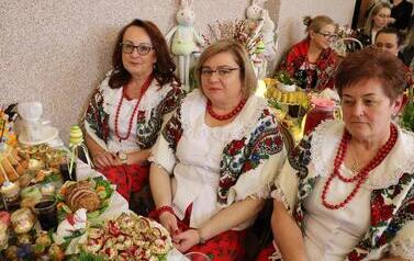 Zdjęcia ukazują bogactwo podkarpackiego folkloru. Członkinie KGW z całej gminy prezentują się w tradycyjnych strojach: białych, haftowanych bluzkach z kryzami oraz charakterystycznych czerwonych koralach. Siedzą przy stołach uginających się od tradycyjnyc