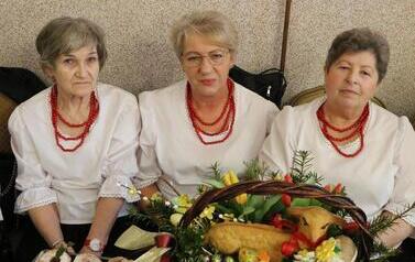 Zdjęcia ukazują bogactwo podkarpackiego folkloru. Członkinie KGW z całej gminy prezentują się w tradycyjnych strojach: białych, haftowanych bluzkach z kryzami oraz charakterystycznych czerwonych koralach. Siedzą przy stołach uginających się od tradycyjnyc