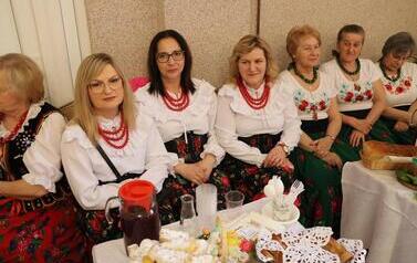 Zdjęcia ukazują bogactwo podkarpackiego folkloru. Członkinie KGW z całej gminy prezentują się w tradycyjnych strojach: białych, haftowanych bluzkach z kryzami oraz charakterystycznych czerwonych koralach. Siedzą przy stołach uginających się od tradycyjnyc