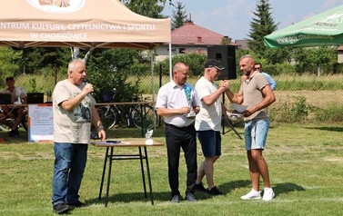 Seria dynamicznych i pozowanych zdjęć z amatorskiego turnieju piłki nożnej, kt&oacute;ry odbył się w pogodny, słoneczny dzień na trawiastym boisku otoczonym brzozami. Zdjęcia przedstawiają pełny przebieg wydarzenia sportowego. Galeria zawiera pozowane fotografie