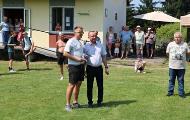 Seria dynamicznych i pozowanych zdjęć z amatorskiego turnieju piłki nożnej, kt&oacute;ry odbył się w pogodny, słoneczny dzień na trawiastym boisku otoczonym brzozami. Zdjęcia przedstawiają pełny przebieg wydarzenia sportowego. Galeria zawiera pozowane fotografie