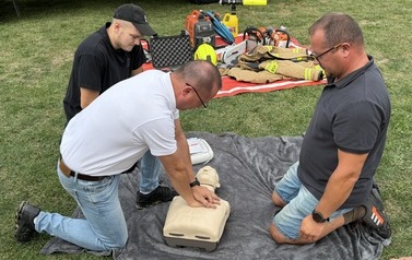 Seria fotografii dokumentujących plenerowe wydarzenie edukacyjne &bdquo;Akademia OLiOC&rdquo;, kt&oacute;re odbyło się na boisku trawiastym w Kopytowej pod patronatem Gminy Chork&oacute;wka. Zdjęcia przedstawiają praktyczne warsztaty z pierwszej pomocy przedmedycznej oraz prezenta