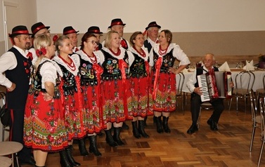 Zdjęcia z uroczystości Złotych God&oacute;w w Domu Ludowym w Zręcinie. Przedstawiają one występy męskiej sekcji Zespołu Śpiewaczego &bdquo;Chorkowianie&rdquo; w tradycyjnych strojach ludowych, oficjalne wystąpienie władz gminy Chork&oacute;wka oraz pamiątkowe kadry z jubilatami odznaczonymi Medalami za Długoletnie Pożycie Małżeńskie.