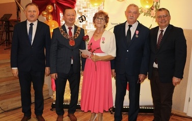 Zdjęcia z uroczystości Złotych God&oacute;w w Domu Ludowym w Zręcinie. Przedstawiają one występy męskiej sekcji Zespołu Śpiewaczego &bdquo;Chorkowianie&rdquo; w tradycyjnych strojach ludowych, oficjalne wystąpienie władz gminy Chork&oacute;wka oraz pamiątkowe kadry z jubilatami odznaczonymi Medalami za Długoletnie Pożycie Małżeńskie.