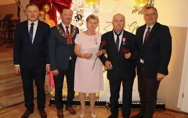 Zdjęcia z uroczystości Złotych God&oacute;w w Domu Ludowym w Zręcinie. Przedstawiają one występy męskiej sekcji Zespołu Śpiewaczego &bdquo;Chorkowianie&rdquo; w tradycyjnych strojach ludowych, oficjalne wystąpienie władz gminy Chork&oacute;wka oraz pamiątkowe kadry z jubilatami odznaczonymi Medalami za Długoletnie Pożycie Małżeńskie.
