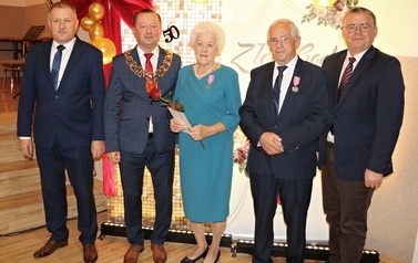 Zdjęcia z uroczystości Złotych God&oacute;w w Domu Ludowym w Zręcinie. Przedstawiają one występy męskiej sekcji Zespołu Śpiewaczego &bdquo;Chorkowianie&rdquo; w tradycyjnych strojach ludowych, oficjalne wystąpienie władz gminy Chork&oacute;wka oraz pamiątkowe kadry z jubilatami odznaczonymi Medalami za Długoletnie Pożycie Małżeńskie.