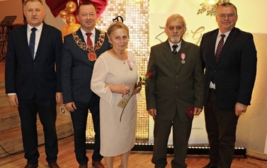 Zdjęcia z uroczystości Złotych God&oacute;w w Domu Ludowym w Zręcinie. Przedstawiają one występy męskiej sekcji Zespołu Śpiewaczego &bdquo;Chorkowianie&rdquo; w tradycyjnych strojach ludowych, oficjalne wystąpienie władz gminy Chork&oacute;wka oraz pamiątkowe kadry z jubilatami odznaczonymi Medalami za Długoletnie Pożycie Małżeńskie.