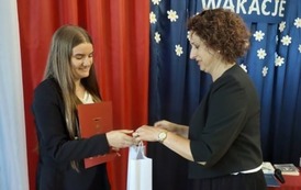 Nagrodzona uczennica odbiera nagrodę. 