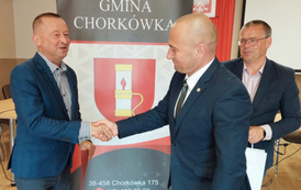 Na zdjęciu nagrodzony Piotr Drozd,  W&oacute;jt Gminy Chork&oacute;wka oraz zastępca na tle banneru z herbem gminy. 