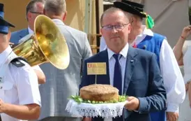 Widoczny na zdjęciu w&oacute;jt gminy elegancko ubrany trzymający w dłoniach chleb. 