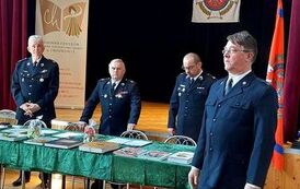 Przedstawiciele Straży Pożarnej. Czterech mężczyzn w umundurowaniu przy stole prezydialnym.  